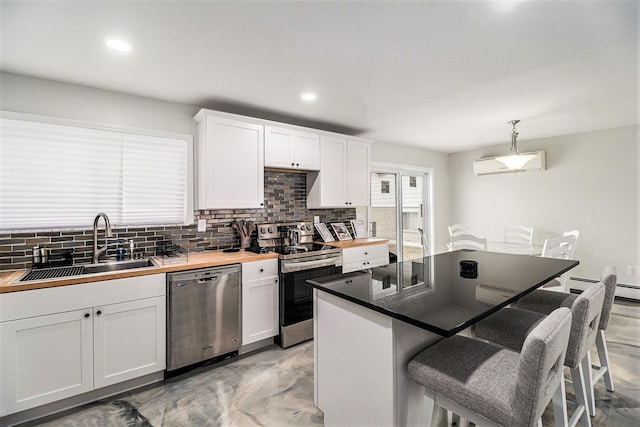 kitchen featuring a breakfast bar, pendant lighting, white cabinetry, sink, and stainless steel appliances