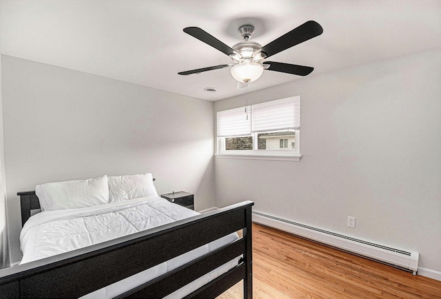 bedroom with a baseboard radiator, ceiling fan, and light wood-type flooring