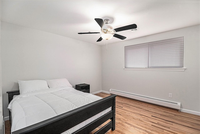 bedroom with a baseboard heating unit, light hardwood / wood-style floors, and ceiling fan