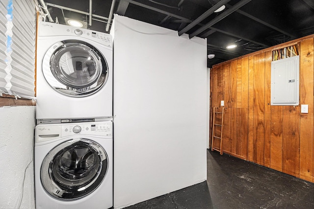 clothes washing area with stacked washer and dryer and electric panel