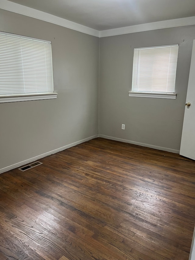 spare room with crown molding and dark wood-type flooring