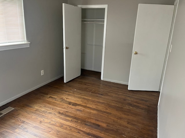 unfurnished bedroom featuring dark hardwood / wood-style floors and a closet