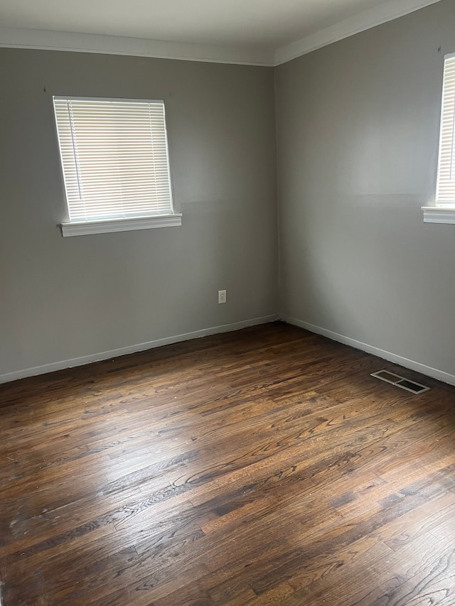 empty room featuring dark hardwood / wood-style flooring and ornamental molding