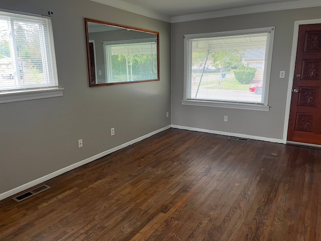 spare room with a healthy amount of sunlight, ornamental molding, and dark wood-type flooring