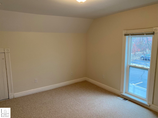 spare room with carpet floors and vaulted ceiling