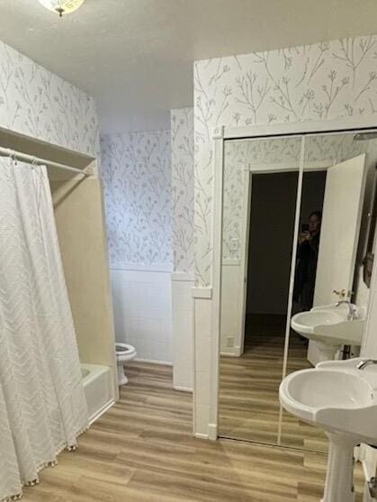 bathroom with hardwood / wood-style floors, shower / bath combo, and toilet