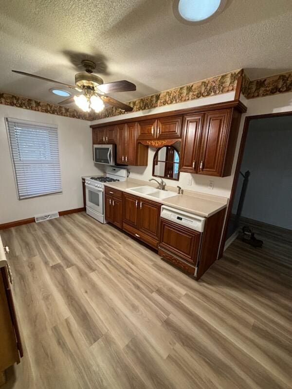 kitchen featuring white range with gas stovetop, a textured ceiling, light wood-type flooring, and sink