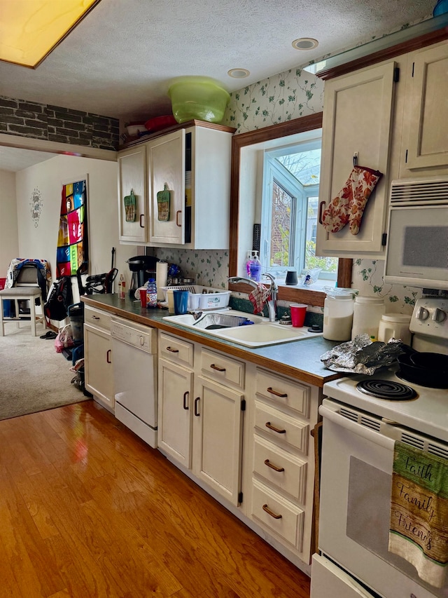 kitchen with light wood-type flooring, a textured ceiling, white appliances, sink, and white cabinets