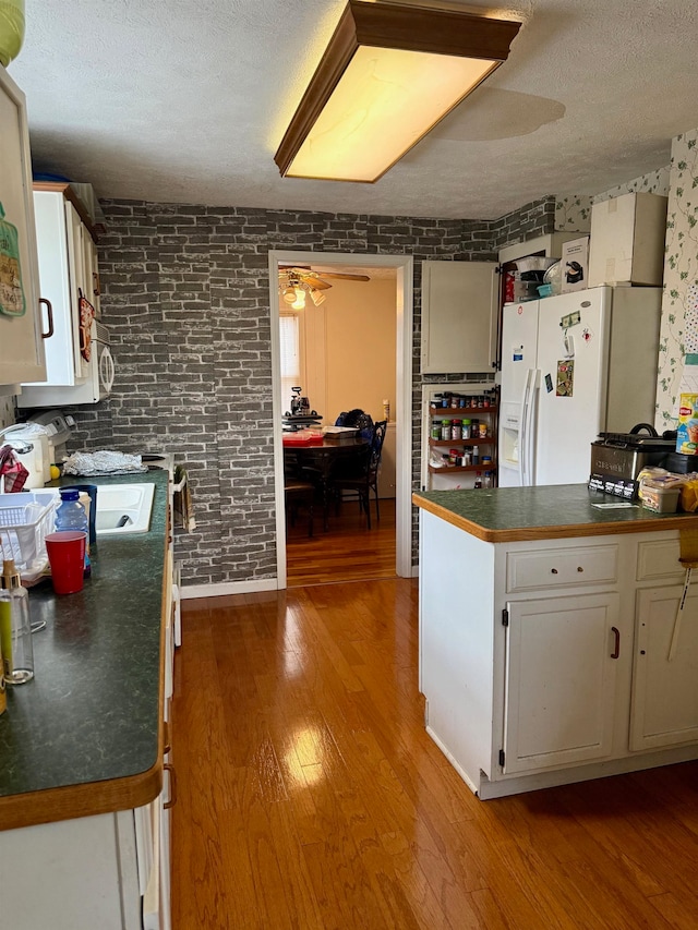 kitchen featuring a textured ceiling, white appliances, ceiling fan, white cabinets, and light hardwood / wood-style floors