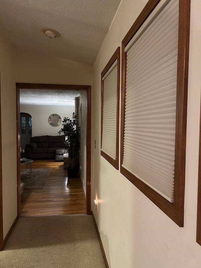 corridor with hardwood / wood-style floors and a textured ceiling