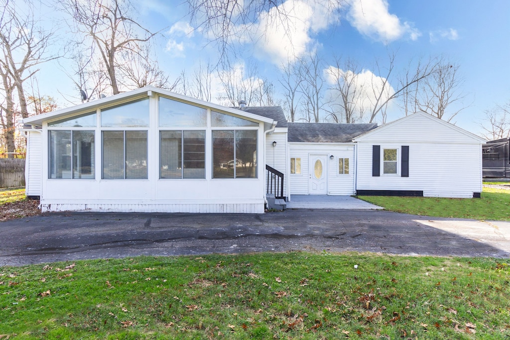 view of front of house featuring a sunroom and a front yard