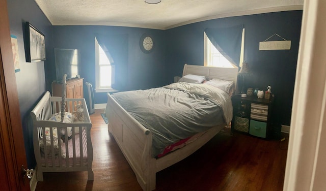 bedroom with dark hardwood / wood-style flooring, a textured ceiling, and multiple windows