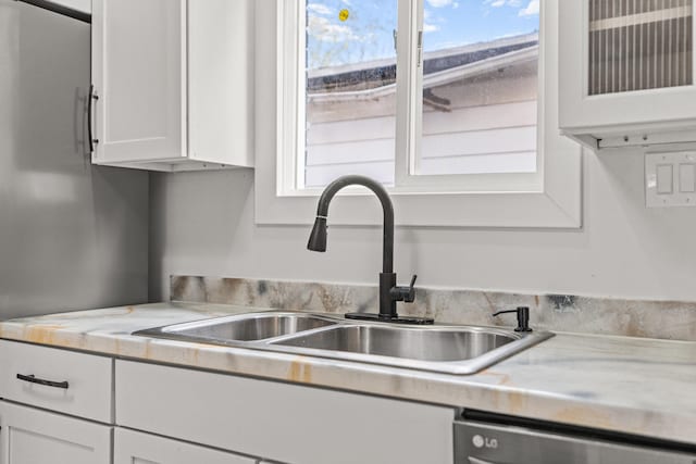 kitchen with dishwasher, white cabinets, and sink