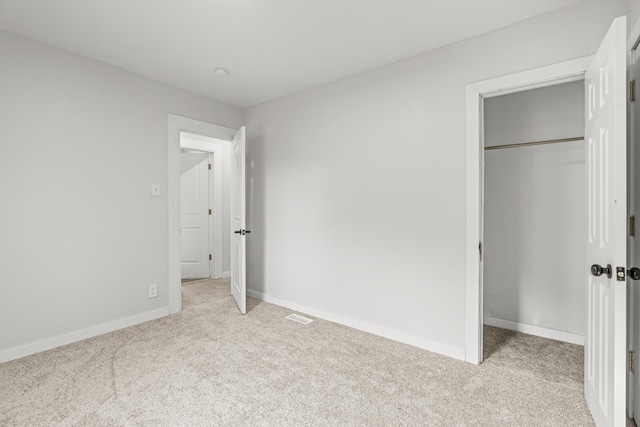 unfurnished bedroom with light carpet and a closet