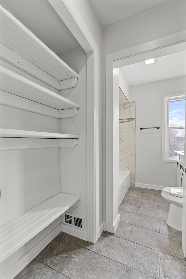 bathroom with tiled shower / bath combo and toilet