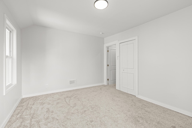 unfurnished room with light colored carpet and lofted ceiling