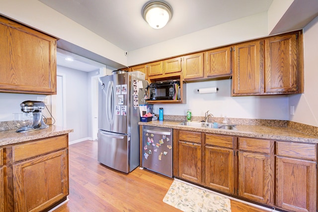 kitchen with sink, stainless steel appliances, and light hardwood / wood-style floors