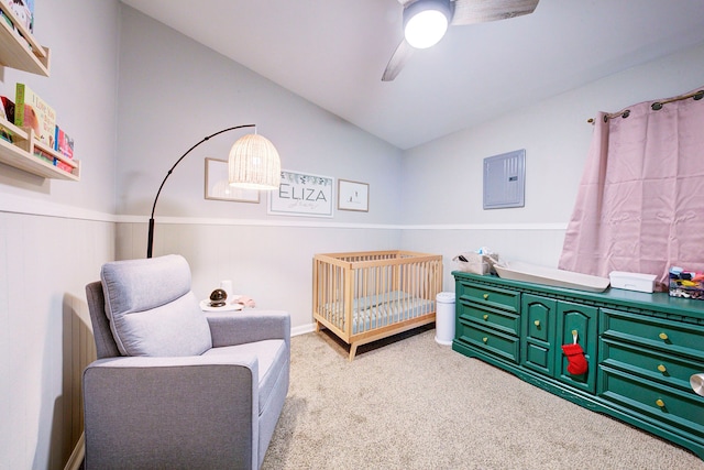 carpeted bedroom featuring ceiling fan, a crib, lofted ceiling, and electric panel