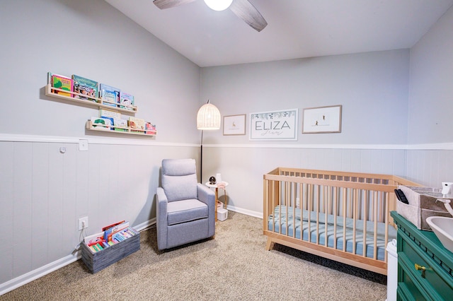 carpeted bedroom featuring a crib and ceiling fan