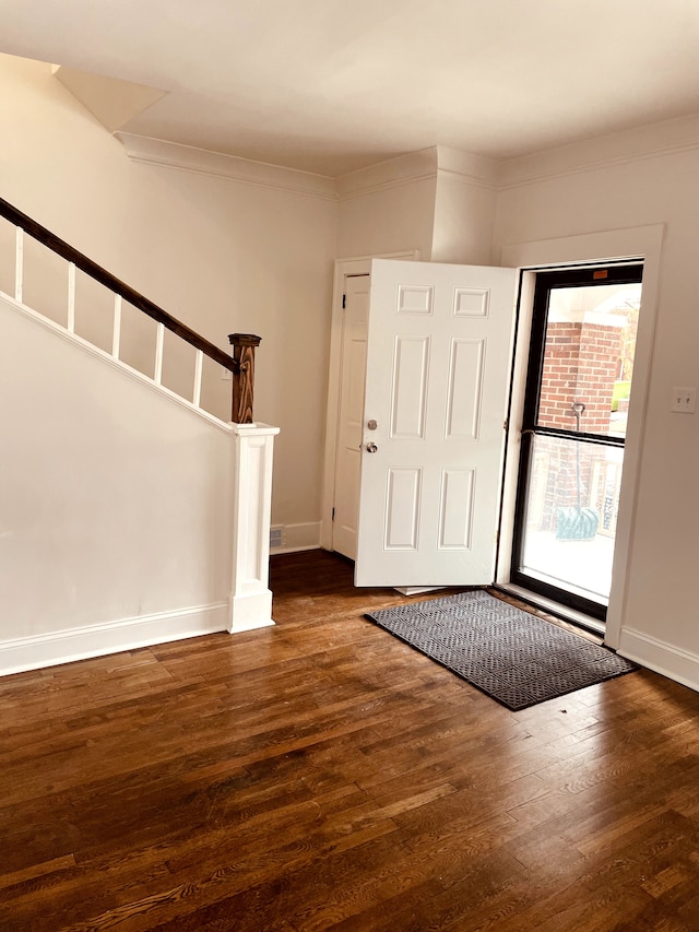 foyer entrance with ornamental molding and dark hardwood / wood-style flooring