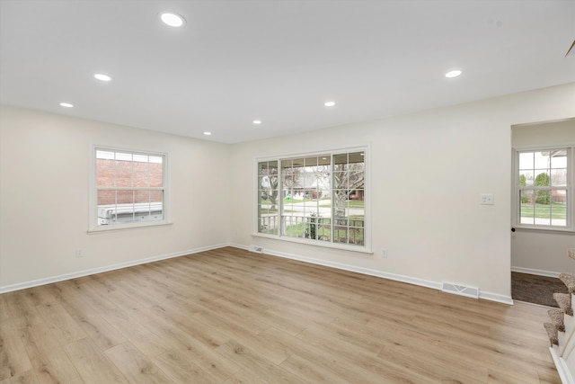 empty room with a healthy amount of sunlight and light hardwood / wood-style flooring