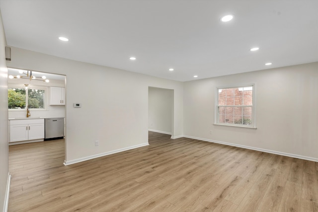 spare room with light hardwood / wood-style floors, sink, and an inviting chandelier