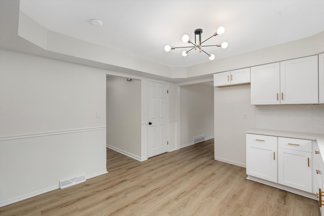 kitchen with white cabinets, backsplash, a chandelier, and light hardwood / wood-style flooring