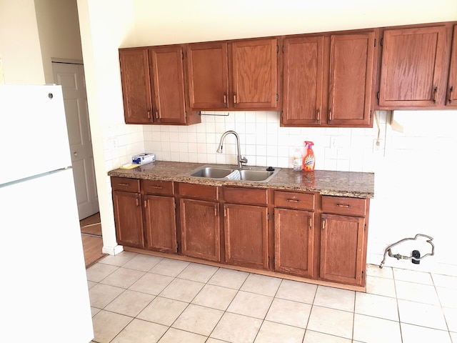 kitchen with light tile patterned floors, white refrigerator, tasteful backsplash, and sink