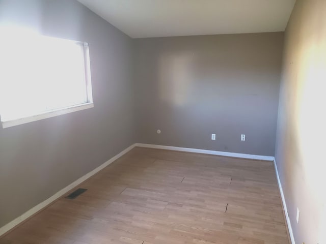 spare room featuring lofted ceiling and light hardwood / wood-style flooring