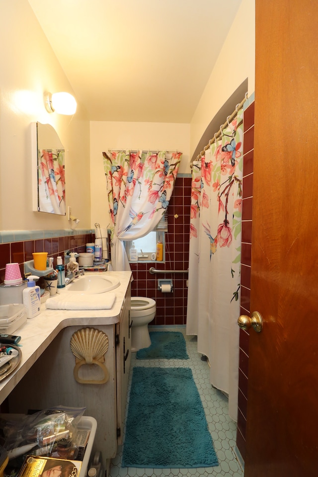 bathroom with vanity, toilet, and tile walls