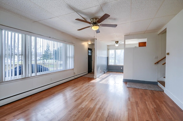 empty room featuring hardwood / wood-style floors, ceiling fan, a paneled ceiling, and baseboard heating