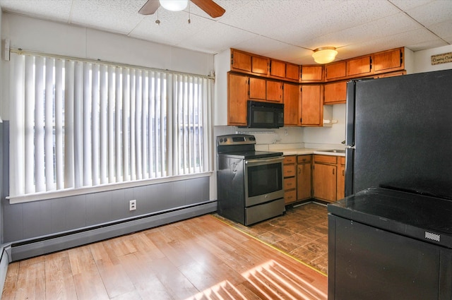 kitchen featuring ceiling fan, sink, a baseboard heating unit, light hardwood / wood-style floors, and appliances with stainless steel finishes