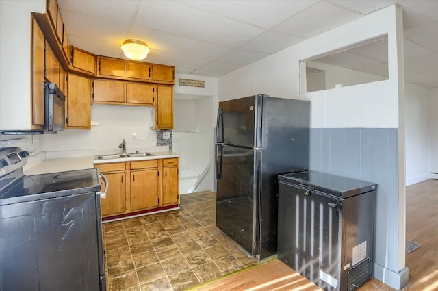 kitchen with black appliances, a paneled ceiling, dark hardwood / wood-style flooring, and sink