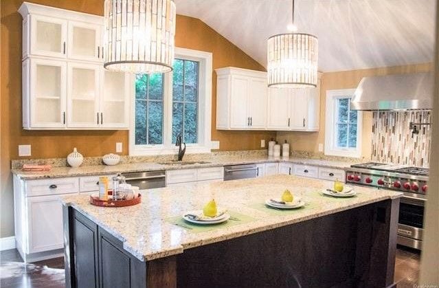 kitchen featuring pendant lighting, white cabinetry, appliances with stainless steel finishes, and vaulted ceiling