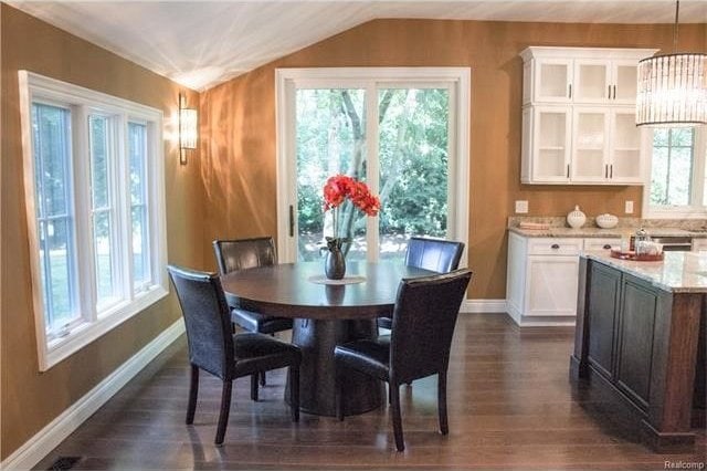 dining room with dark hardwood / wood-style floors, a chandelier, and vaulted ceiling