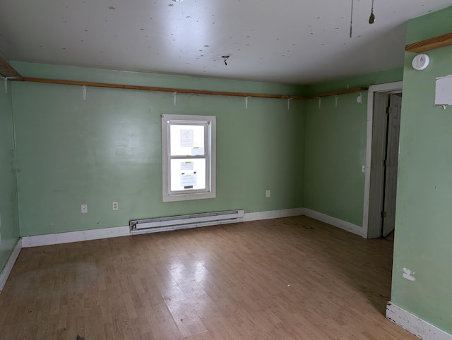 empty room featuring light wood-type flooring and a baseboard heating unit