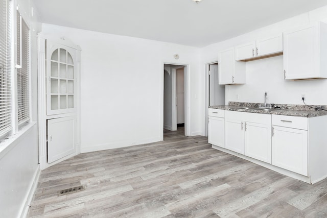 kitchen featuring white cabinets, light hardwood / wood-style floors, and sink