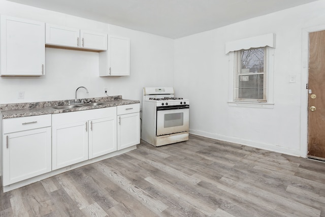 kitchen featuring light wood-type flooring, white cabinetry, gas range gas stove, and sink