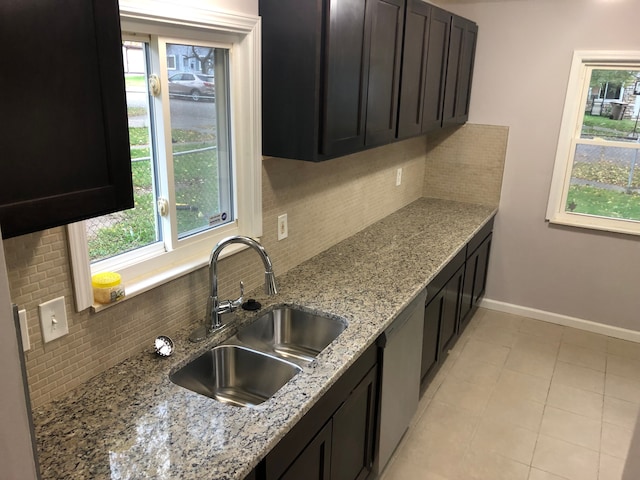 kitchen with light stone countertops, dark brown cabinets, tasteful backsplash, and sink