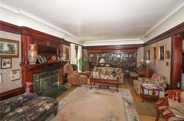 living room with wood-type flooring, crown molding, and a tiled fireplace