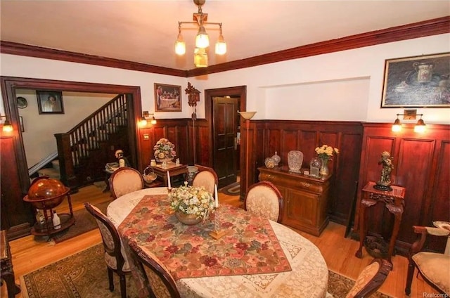 dining area featuring crown molding, light hardwood / wood-style flooring, and an inviting chandelier