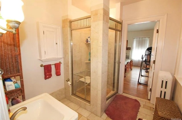 bathroom with hardwood / wood-style flooring, radiator heating unit, and walk in shower