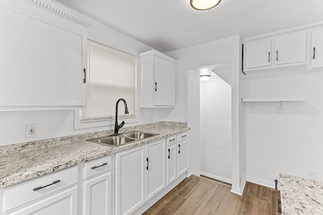 kitchen with light stone counters, sink, white cabinets, and dark hardwood / wood-style floors