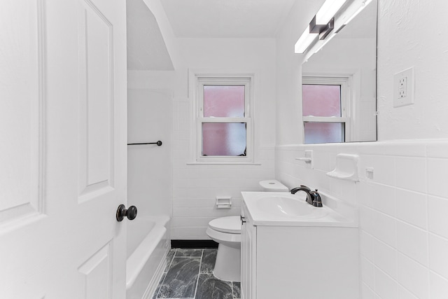 bathroom featuring vanity, tile walls, and toilet