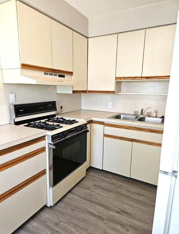 kitchen featuring light wood-type flooring, white appliances, white cabinetry, and sink