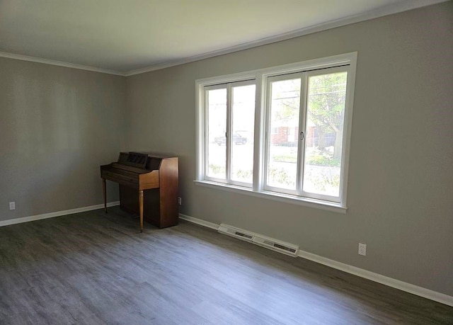 empty room with dark hardwood / wood-style floors, ornamental molding, and a wealth of natural light