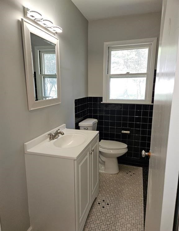 bathroom featuring tile patterned flooring, vanity, tile walls, and toilet