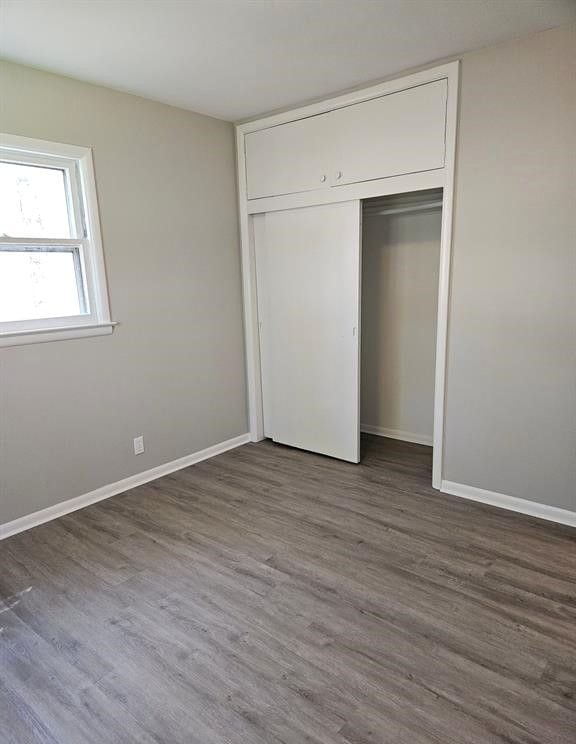 unfurnished bedroom featuring a closet and dark hardwood / wood-style flooring