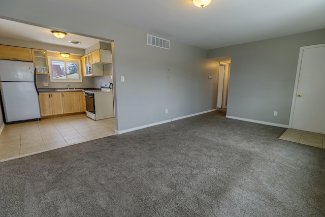 kitchen featuring light brown cabinets, light colored carpet, white appliances, and sink