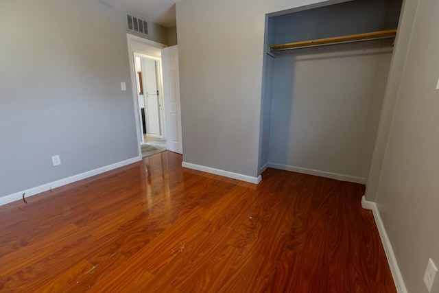 unfurnished bedroom featuring dark hardwood / wood-style flooring and a closet